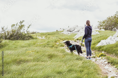 A young woman hiking with dog and taking pictures with phone in the beautiful landscape.