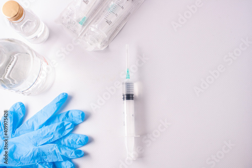 Syringes, vaccine vials, medical gloves on a white background.