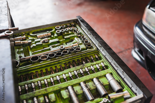 High angle of tool box with kit of various drill bits placed near vehicle in garage photo