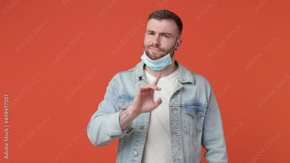 Smiling bearded young man in denim jacket isolated on orange background. People lifestyle concept. Showing how to correctly wear sterile face mask safe from coronavirus virus covid-19 thumb up like Smiling bearded young man in denim jacket isolated on orange background. People lifestyle concept. Showing how to correctly wear sterile face mask safe from coronavirus virus covid-19 thumb up like