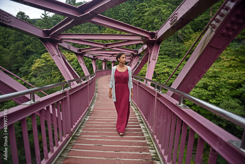 Young caucasian woman walking Ayatori-hashi Bridge (Cat¬•s cradle), designed by Ikebana master Hiroshi Teshigahara, Kaga, Japan photo