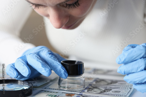 Canvas Print Woman in rubber gloves looking at dollar bills through magnifying glass