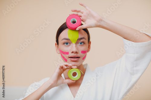 Beautiful woman applying tape lifting treatment on face photo