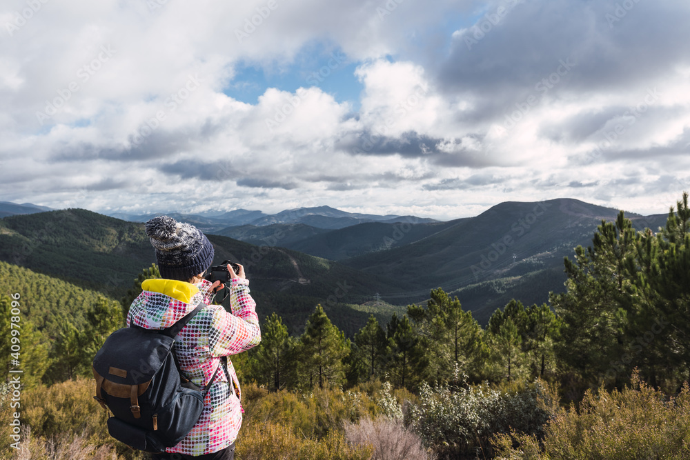 Young and attractive female with a colourful jacket taking landscape photos in a forest with a digital camera. Young and attractive female with a colourful jacket taking landscape photos in a forest with a digital camera.