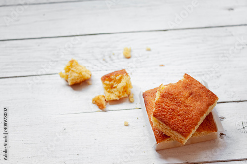 Top view composition with pieces of yummy sweet typical Spanish sobao pasiego cake placed on white wooden plank surface photo