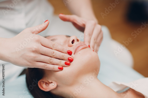 Beautiful young woman getting face treatment massage at beauty spa salon.