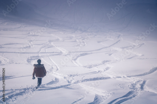 Foto jeune homme dans la neige devant une piste et des traces partant dans toutes les