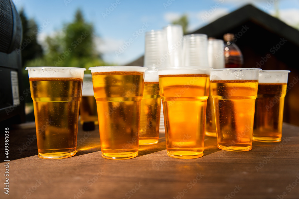 Plastic cups with lager beer on the table for group outdoors Plastic cups with lager beer on the table for group outdoors