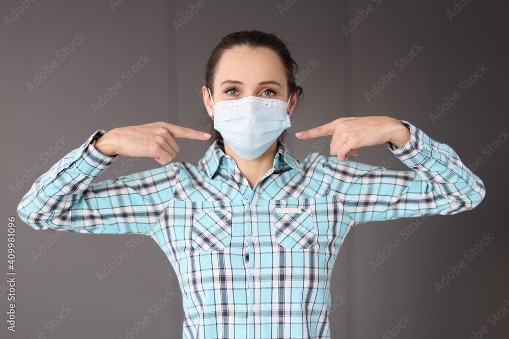 Woman showing her fingers to medical protective mask on her face Woman showing her fingers to medical protective mask on her face
