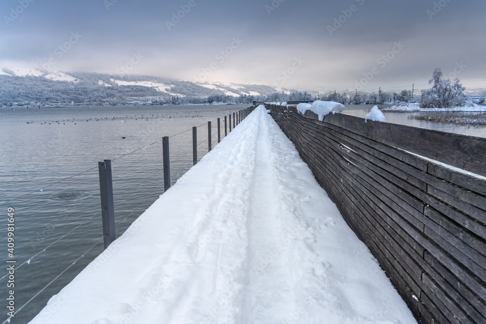 Snow-covered pedestrian wooden bridge (Holzsteg) crossing the Zurich Lake at its narrowest point between Hurden (Seedam) and Rapperswil, Switzerland