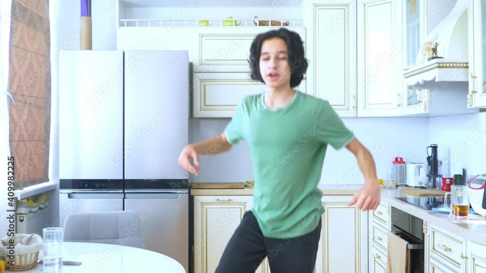 handsome curly guy dancer cheerfully dancing at home in the kitchen . handsome curly guy dancer cheerfully dancing at home in the kitchen .