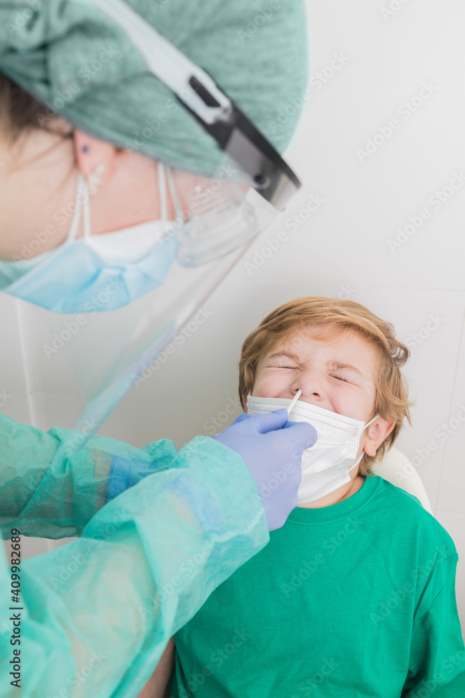 Side view of medic in protective uniform conducting PCR test on COVID virus while taking nasal swab from kid Side view of medic in protective uniform conducting PCR test on COVID virus while taking nasal swab from kid
