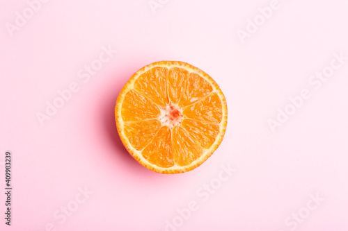 Orange slice on a pink minimal background. Bright juicy orange on a pink blank isolated background. Summer, sun, health concept.