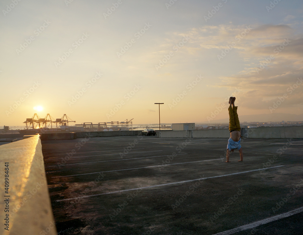 Fototapeta premium Man does Handstand on top floor of parking garage above the City of Honolulu