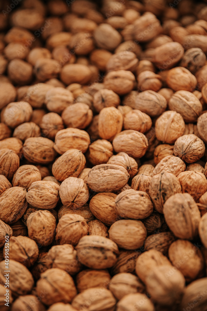 Closeup of scattered pile of natural unpeeled brown walnuts for food and cooking concept background Closeup of scattered pile of natural unpeeled brown walnuts for food and cooking concept background