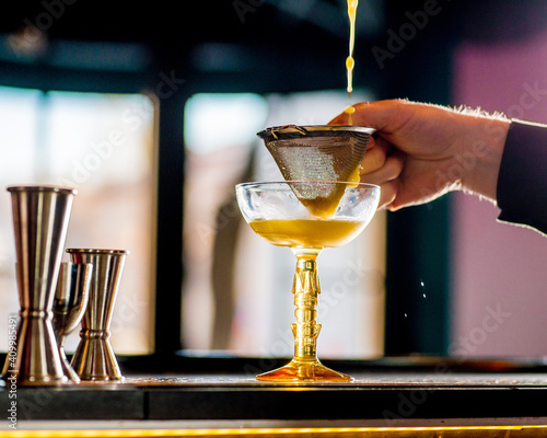 bartender pours a cocktail into a glass photo