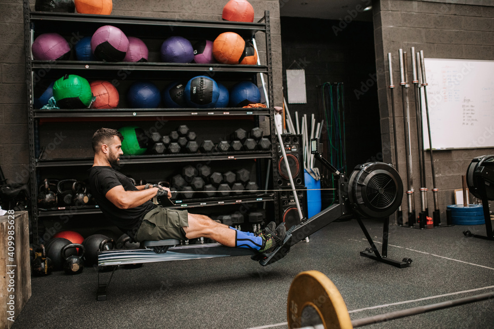 © Raquel Arocena/ADDICTIVE STOCK - Side view of athletic male with strong body doing exercises on rowing machine in modern sports club © Raquel Arocena/ADDICTIVE STOCK - Side view of athletic male with strong body doing exercises on rowing machine in modern sports club