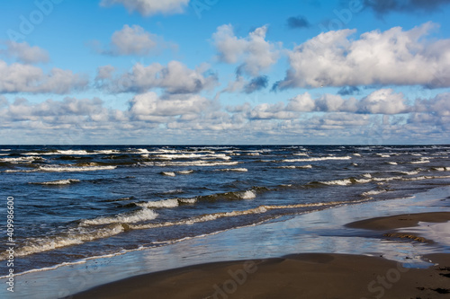 White cumulus clouds in sky over wavy Baltic sea water landscape. Many small clouds above sea.