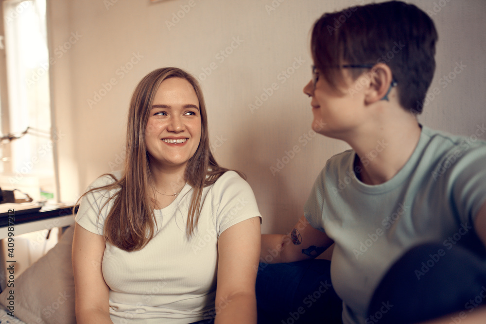 Couple of lesbian females resting on soft bed and laughing while looking at each other and having fun at home Couple of lesbian females resting on soft bed and laughing while looking at each other and having fun at home