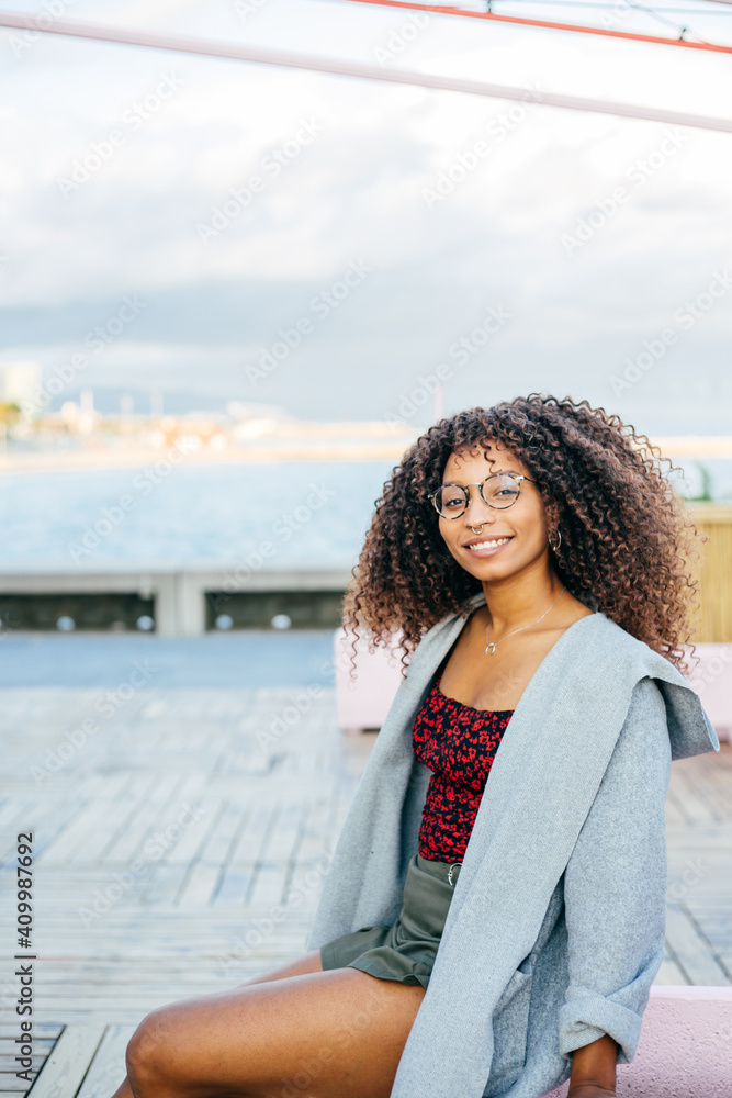 Happy African American female looking away while standing on quay near sea Happy African American female looking away while standing on quay near sea
