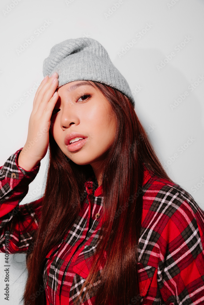 Close-up portrait of cheerful Asian young woman covering her face with her hand Close-up portrait of cheerful Asian young woman covering her face with her hand