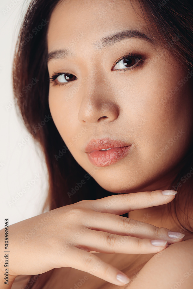 Portrait of naked young Chinese woman looking at camera over white