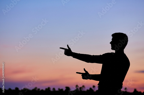 Men silhouette at sunset, human body over natural colorful sky background, hands up having fun
