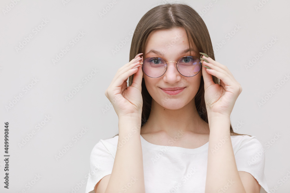 smiling frowning office girl staring at camera through eyeglasses on white background. Young woman adjusting eyewear. Glasses wearing concept smiling frowning office girl staring at camera through eyeglasses on white background. Young woman adjusting eyewear. Glasses wearing concept