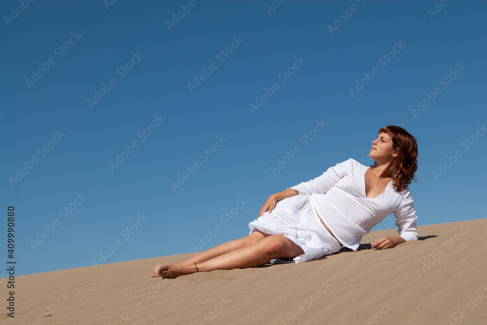 woman dressed in white enjoying in the sand dunes on the sunny day woman dressed in white enjoying in the sand dunes on the sunny day