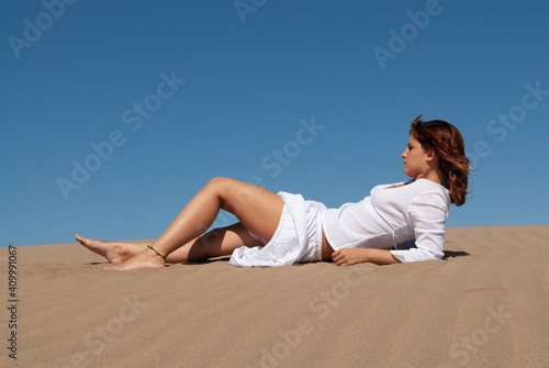 woman dressed in white performing meditation and yoga postures on the sand dunes on sunny day