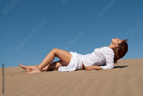woman dressed in white enjoying in the sand dunes on the sunny day