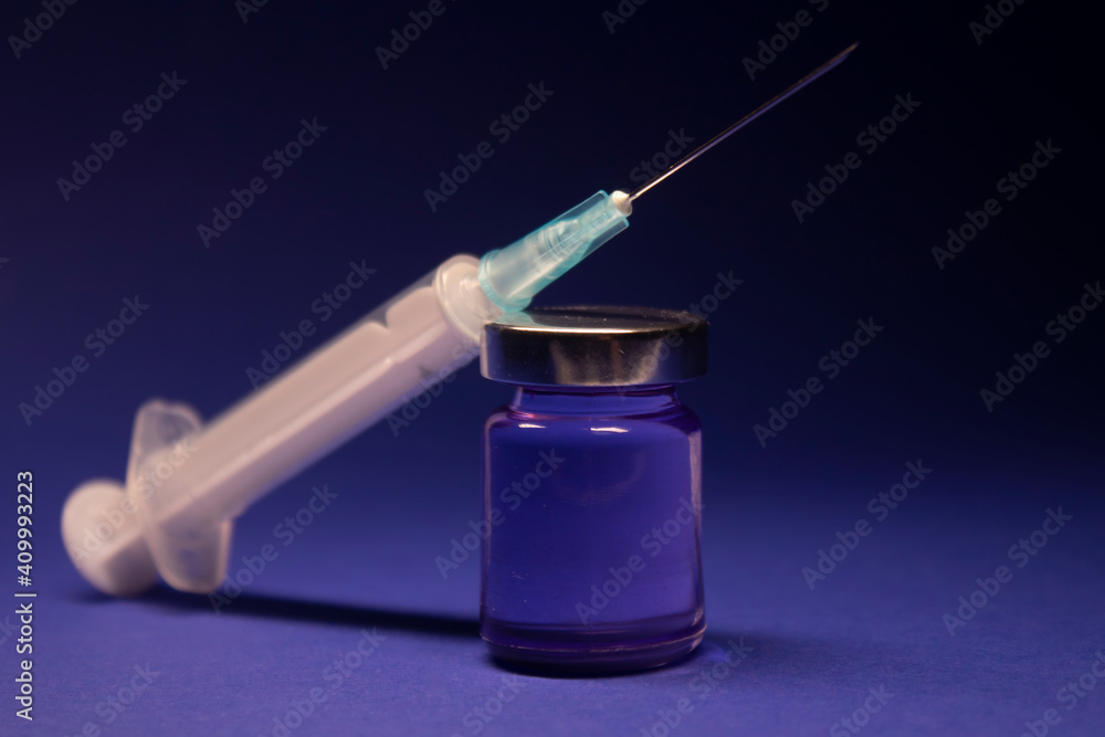 Vaccine bottle phial with no label, medical syringe injection needle. isolated on blue background. Development of coronavirus vaccine COVID-19. cure. World race in researching Vaccine bottle phial with no label, medical syringe injection needle. isolated on blue background. Development of coronavirus vaccine COVID-19. cure. World race in researching