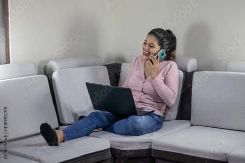 Young woman smiling while talking on cell phone at home