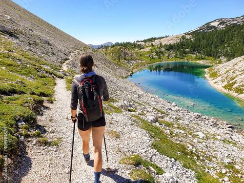 Female hiker hiking along crystal clear mountain lake. photo