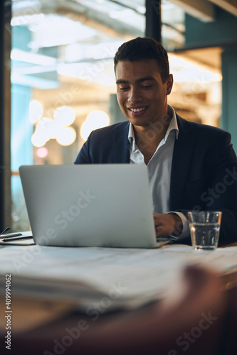 Canvas Print Pleased dark-haired employee typing on his computer