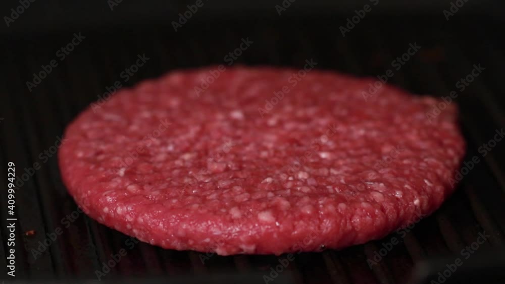 a raw burger patty in placed in a hot pan a raw burger patty in placed in a hot pan