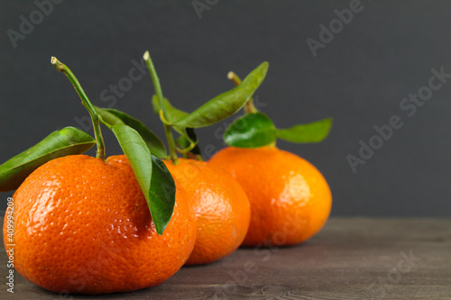 Three tangerines with green leaves on black background