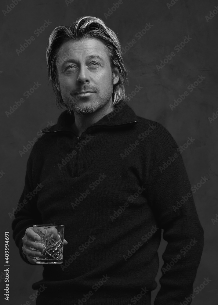 Blonde man in black woolen sweater holding glass of whiskey. Black and white photo. Blonde man in black woolen sweater holding glass of whiskey. Black and white photo.