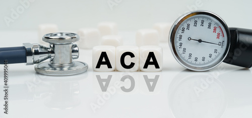 On a reflective white surface lies a stethoscope and cubes with the inscription - ACA photo