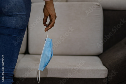 Young woman holding face mask at home