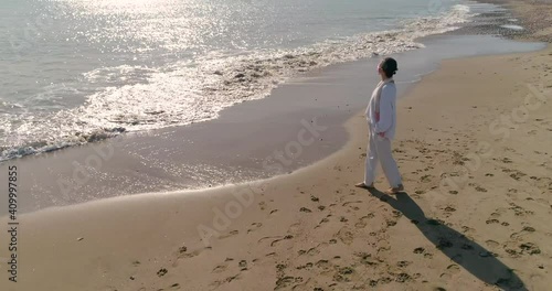 Mujer  senior con mascara covid-19 paseando por la playa sola vestida de blanco photo