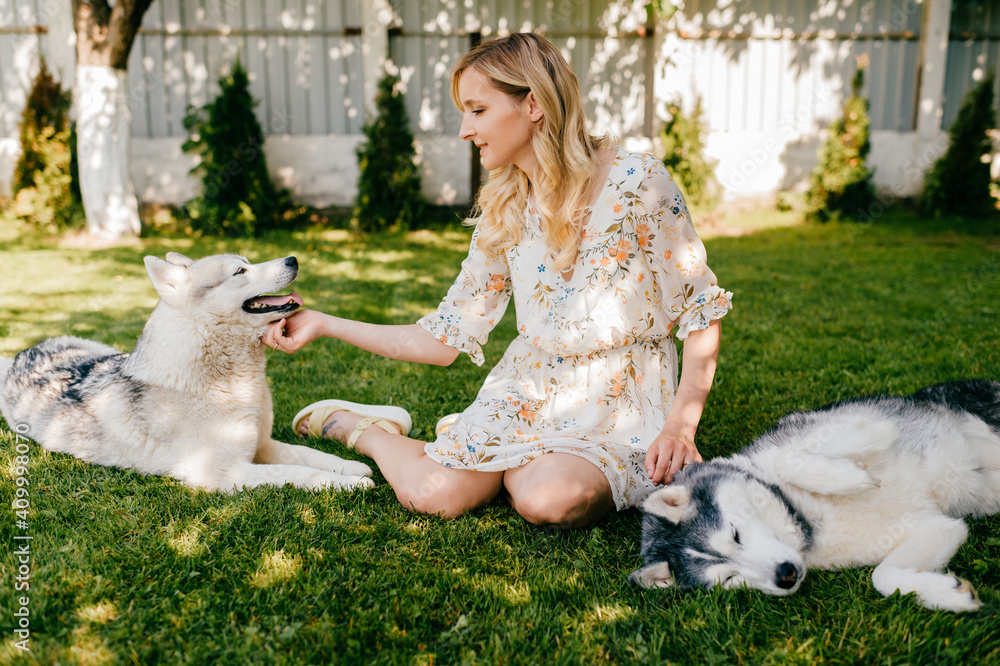 A young romantic woman posing with two dogs on the grass A young romantic woman posing with two dogs on the grass