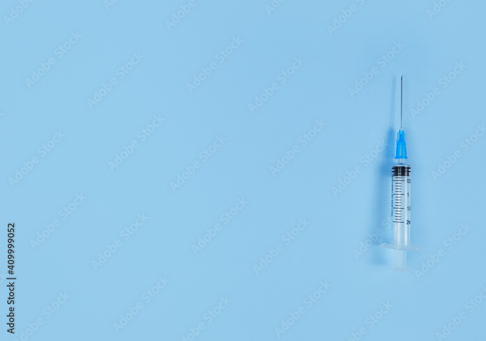Single use syringe on blue background. Simple flat lay with copy space. Single use syringe on blue background. Simple flat lay with copy space.