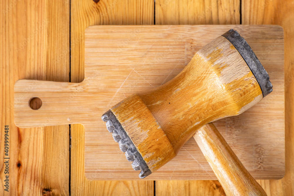 Wooden meat grinder on a chopping board. Wooden kitchen utensils on the kitchen table.