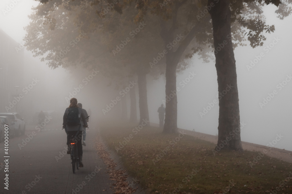 People cycling or waking outdoors during a very foggy, misty day