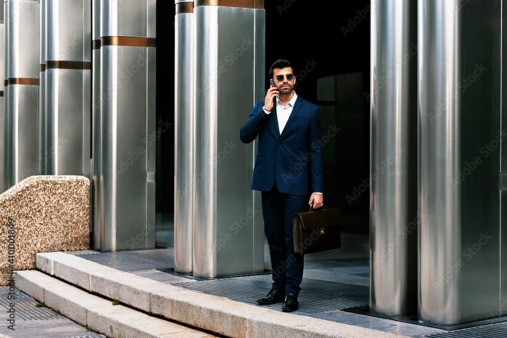 Businessman talking on the phone while leaving his office Businessman talking on the phone while leaving his office