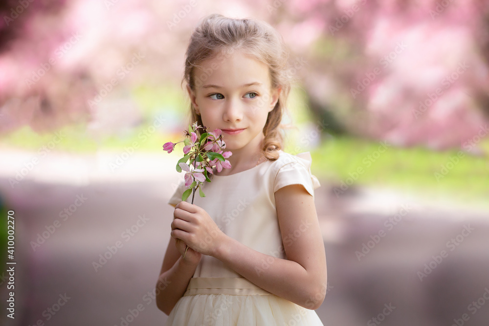 Cute little girl smiles and sniffs flowers in a spring blooming garden, close up Cute little girl smiles and sniffs flowers in a spring blooming garden, close up