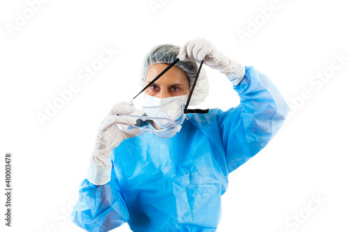 Nurse in coronavirus protective suit, mask and gloves donning protective goggles