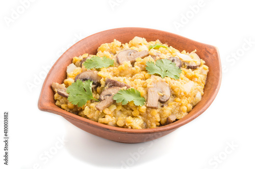 Lentils porridge with champignons. and coriander in a clay bowl isolated on white background. Side view.