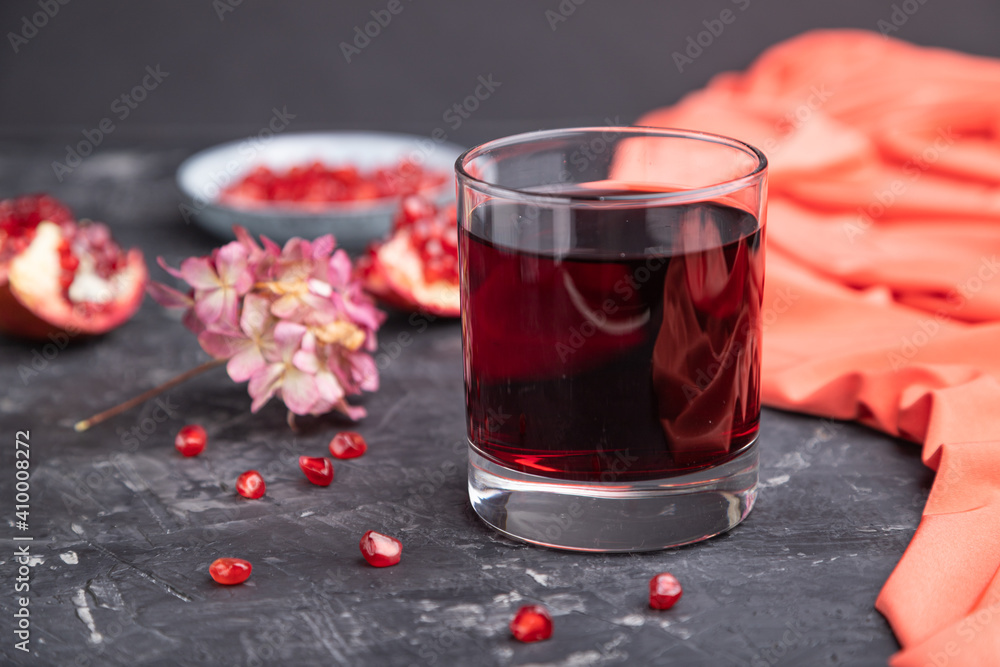 Glass of pomegranate juice on a black concrete background. Side view, selective focus. Glass of pomegranate juice on a black concrete background. Side view, selective focus.